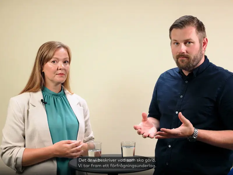 En man och en kvinna står i en studio och samtalar om hur en projektledare avlastar styrelsen i en brf.