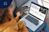 Kvinna sitter i soffan tillsammans med en katt och sin laptop i knät