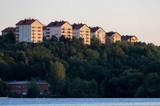 Höghus med bostadsrätter på en grön kulle vid vattnet.