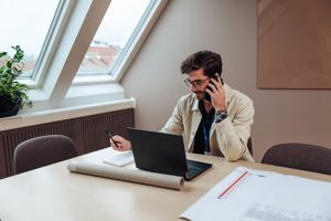 projektledare från sbc pratar i telefon vid ett bord med dator framför sig